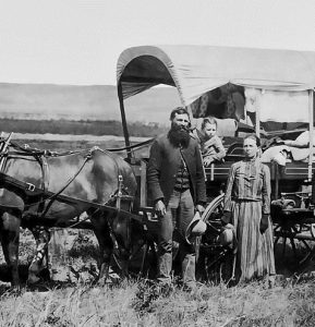 A pioneer family next to their covered wagon